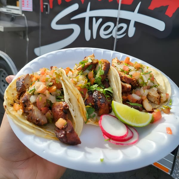Three chicken tacos with pico de gallo, cilantro, lime, and radishes on a white plate.