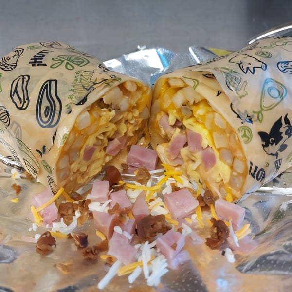 A breakfast burrito from Taquiza Street, cut in half, revealing ham, cheese, and potatoes.