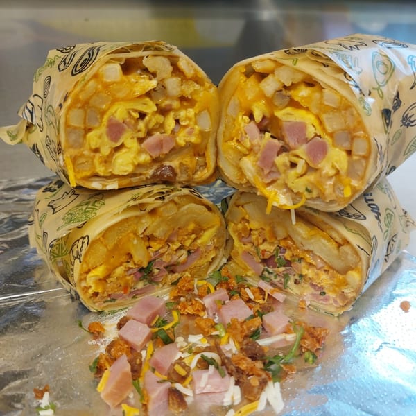 Four Taquiza Street breakfast burritos, cut in half, revealing eggs, ham, potatoes, and cheese.