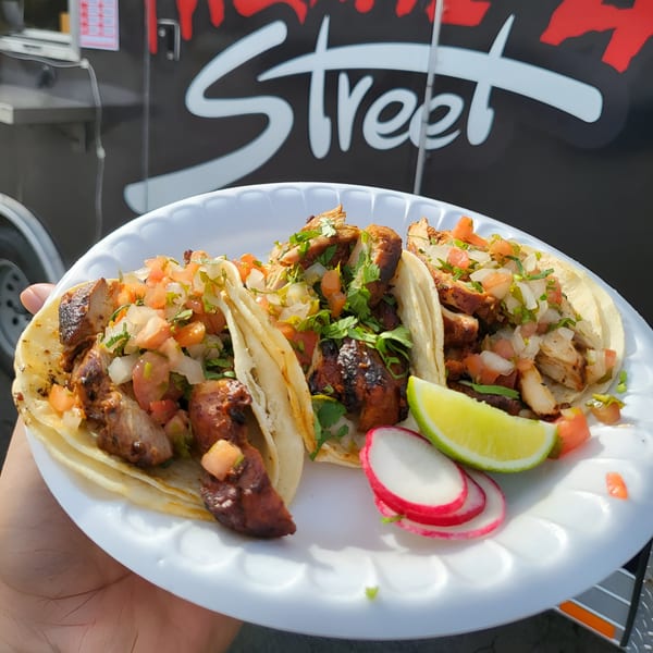 Three Taquiza Street tacos with grilled meat, pico de gallo, cilantro, lime, and radishes.